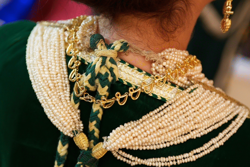 Détail d'un col de caftan marocain orné de perles blanches et de motifs en broderie, mettant en valeur l'artisanat traditionnel.